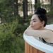 A woman in a swimsuit relaxing in an outdoor hot tub surrounded by nature, embodying leisure and wellness.